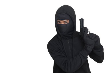 Siyah kapüşonlu ve maskeli gizemli bir adam tabanca tutuyor, silahla ateş ediyor. Gri arkaplanda izole edilmiş resim