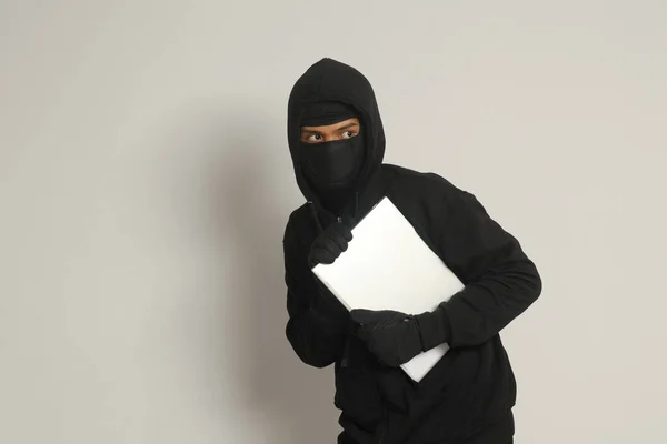 Siyah Kapüşonlu Maskeli Gizemli Hırsız Dizüstü Bilgisayar Çalıp Sıvışıyor Gri — Stok fotoğraf