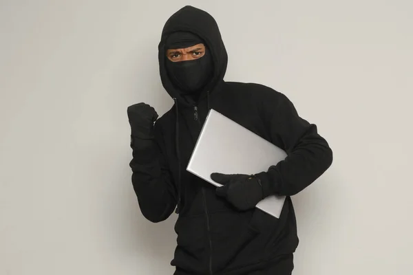 Siyah Kapüşonlu Maskeli Gizemli Hırsız Yumruğunu Kaldırıp Başarıyı Kutlarken Dizüstü — Stok fotoğraf