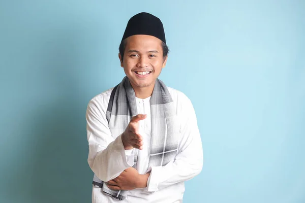 一位身穿白衬衫的迷人的亚洲穆斯林男子伸出手来握手 欢迎某个人的画像 蓝色背景上的孤立图像 — 图库照片