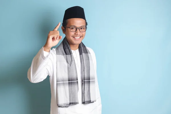 一个年轻的亚洲穆斯林男子的画像 指着他的食指 提醒他该做些什么 广告概念 蓝色背景上的孤立图像 — 图库照片