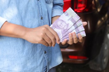 On bin rupiah banknot tutan bir erkek eli. Mali ve tasarruf kavramı