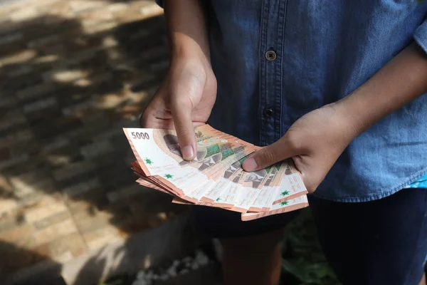 stock image Close up of male hand holding five thousand rupiah money banknote. Financial and savings concept