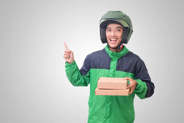 Portrait of Asian online courier driver wearing green jacket and helmet delivering package and box for customer. Isolated image on white background