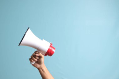 Erkek eli megafon tutuyor, ilan veriyor. Mavi arkaplanda izole edilmiş resim