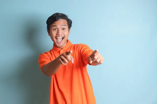 Upphetsad Asiatisk Man Orange Skjorta Ler Och Tittar Kameran Pekar — Stockfoto
