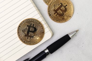 Boş defter ve tükenmez kalemle bir yığın bitcoin 'in üst görüntüsü. Kripto para ticareti kavramı