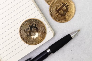 Boş defter ve tükenmez kalemle bir yığın bitcoin 'in üst görüntüsü. Kripto para ticareti kavramı