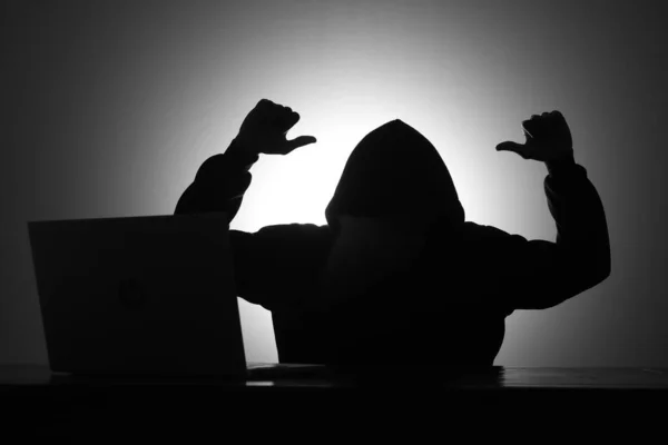Μυστηριώδης Άνθρωπος Φορώντας Μαύρη Κουκούλα Χρησιμοποιώντας Φορητό Υπολογιστή Ενώ Κοροϊδεύοντας — Φωτογραφία Αρχείου