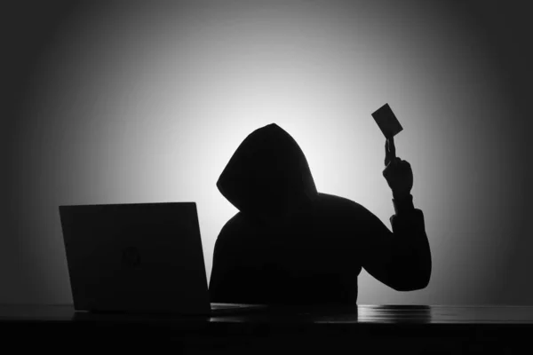 Karanlık Odada Siyah Kapüşonlu Dizüstü Bilgisayar Kullanan Kredi Kartı Tutan — Stok fotoğraf