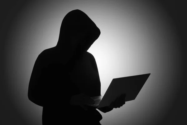 Karanlık Odada Dizüstü Bilgisayar Kullanan Siyah Kapüşonlu Gizemli Bir Adam — Stok fotoğraf