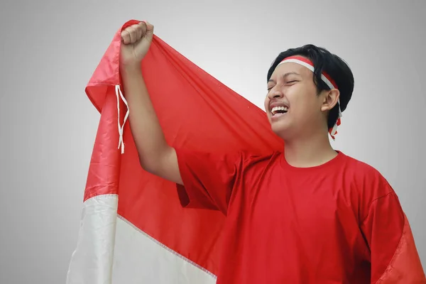 身穿T恤衫 头戴红白缎带 肩上挂着国旗作为斗篷的有魅力的亚洲男子的画像 举起拳头 庆祝印度尼西亚独立日 灰度上的孤立图像 — 图库照片