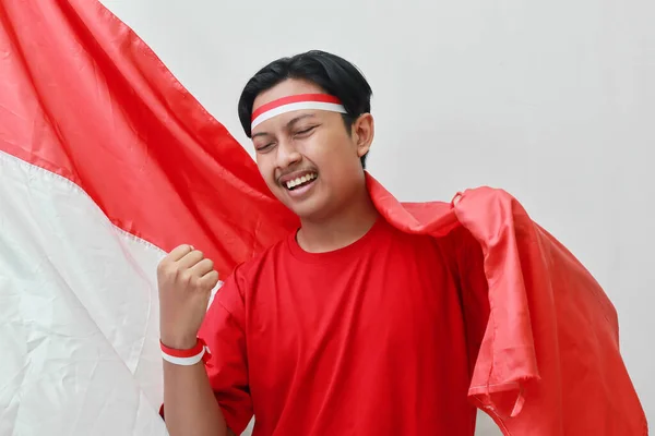 身穿T恤衫 头戴红白相间丝带的亚洲男子的画像 用拳头升起国旗 庆祝印尼独立日 灰色背景上的孤立图像 — 图库照片