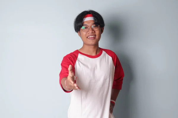 머리에 빨간색과 리본이있는 티셔츠에 매력적인 아시아 남자의 초상화 셰이크에 도달하고 — 스톡 사진