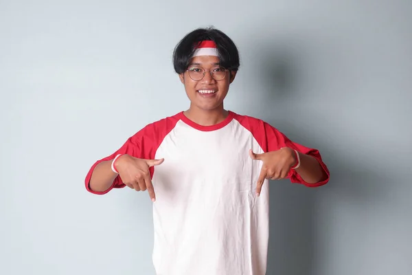 Портрет Привабливого Азіатського Чоловіка Футболці Червоно Білою Стрічкою Голові Вказуючи — стокове фото