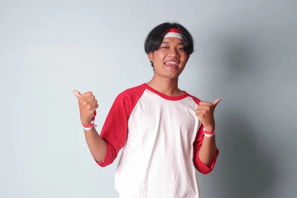 Portrét Atraktivního Asiata Tričku Červenou Bílou Stuhou Hlavě Ukazující Dobré — Stock fotografie