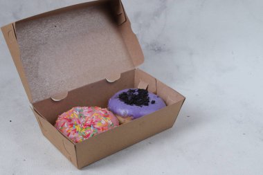 Küçük karton kutuda farklı tatlarda lezzetli tatlı çörekler. Beyaz arkaplanda izole edilmiş resim