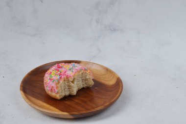 Tahta tabakta servis edilen arta kalan lezzetli, tatlı, pembe çilekli ve serpilmiş çörekler. Beyaz arkaplanda izole edilmiş resim