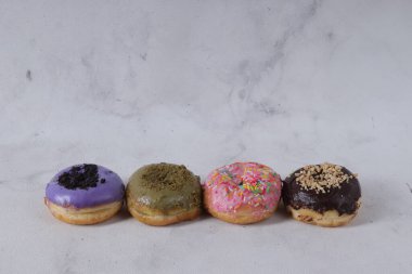 Masada farklı tatlar bulunan lezzetli çörekler. Beyaz arkaplanda izole edilmiş resim