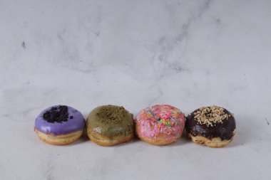 Masada farklı tatlar bulunan lezzetli çörekler. Beyaz arkaplanda izole edilmiş resim