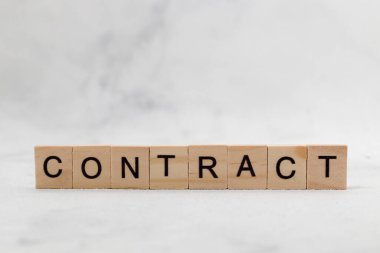 Beyaz arka planda tahta küp harf bloğunun sözleşme sözcüğünün en üst görüntüsü. İş konsepti