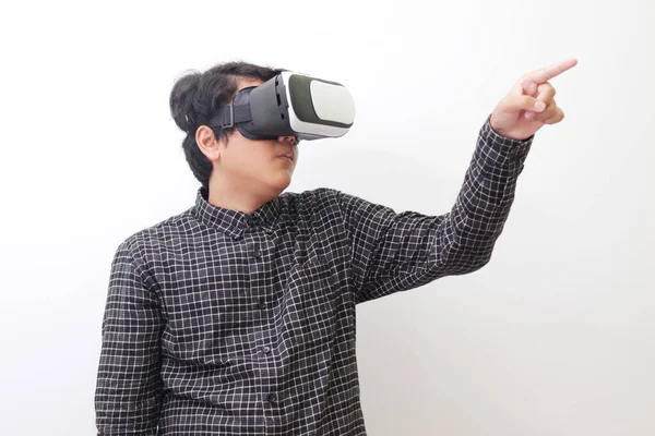 stock image Portrait of Asian man in black plaid shirt using Virtual Reality (VR) glasses and trying to touch something in front of him. Isolated image on white background