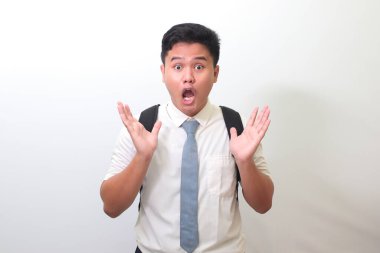 Endonezyalı lise öğrencisi beyaz gömlek giyiyor ve yüzünü ellerle kapatıyor. Beyaz arkaplanda izole edilmiş resim