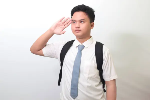 Indonesian senior high school student wearing white shirt uniform with gray tie giving salute pose with hand during flag ceremony. Isolated image on white background