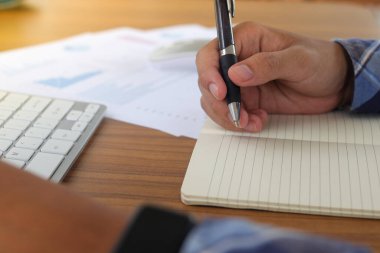 İşletme grafiği ve çizelgesi olan analiz verilerini sabah ofis masasında gösteren ve dizüstü bilgisayarda çalışan erkek serbest işçi elini kapat.