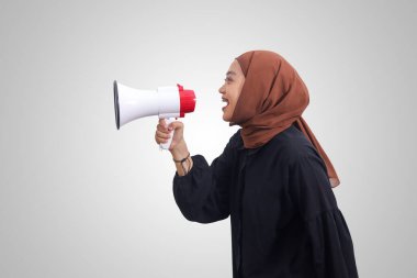 Asyalı tesettürlü kadının portresi rahat gömlekli, yüksek sesle konuşan megafon kullanan, ürünü tanıtan. Reklam konsepti. Beyaz arkaplanda izole edilmiş resim
