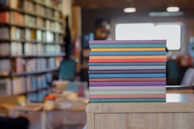 Kütüphane odasındaki ahşap masanın üzerinde renkli kitaplar yığını. Eğitim ve bilgi kavramı. Okuyacak kitap yığını.