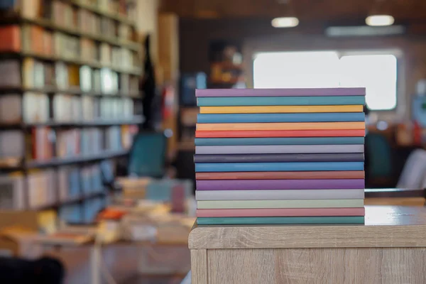 Kütüphane odasındaki ahşap masanın üzerinde renkli kitaplar yığını. Eğitim ve bilgi kavramı. Okuyacak kitap yığını.