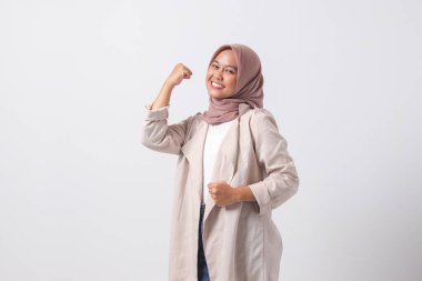 Heyecanlı Asyalı tesettürlü kadın resmi. Sıradan giyinmiş, yumruğunu kaldırmış, başarıyı kutluyor. İş kadını konsepti. Beyaz arkaplanda izole edilmiş resim