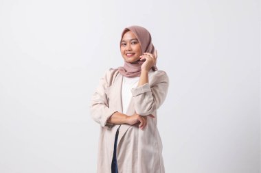 Çekici Asyalı tesettürlü kadın portresi rahat giyinmiş, kendine güvenen, profesyonel el hareketleriyle poz veren. Beyaz arkaplanda izole