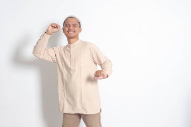 Uyandıktan sonra ellerini ve vücudunu sarkan kafatası şapkalı, Koko gömlekli çok çalışan Asyalı Müslüman adamın portresi. Uyku yoksunluğu konsepti. Beyaz arkaplanda izole edilmiş resim