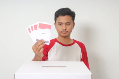 Heyecanlı Asyalı adamın portresi oy pusulasını sandığa yerleştirip koyuyor. Endonezya cumhurbaşkanı ve hükümeti için genel seçimler veya Pemilu. Beyaz arkaplanda izole edilmiş resim