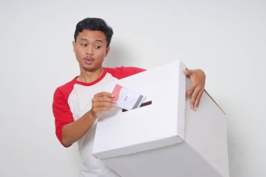 Heyecanlı Asyalı adamın portresi oy pusulasını sandığa yerleştirip koyuyor. Endonezya cumhurbaşkanı ve hükümeti için genel seçimler veya Pemilu. Beyaz arkaplanda izole edilmiş resim