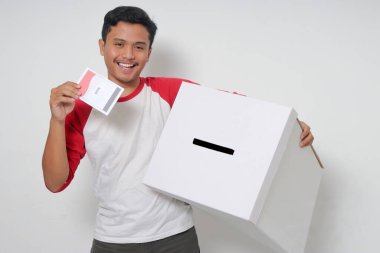 Heyecanlı Asyalı adamın portresi oy pusulasını sandığa yerleştirip koyuyor. Endonezya cumhurbaşkanı ve hükümeti için genel seçimler veya Pemilu. Beyaz arkaplanda izole edilmiş resim