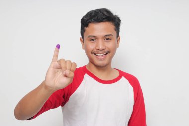 Heyecanlı Asyalı adamın portresi genel seçimlerden sonra mor mürekkebe batırılmış küçük parmağını gösteriyor ya da Endonezya devlet başkanı ve hükümeti için Pemilu 'yu. Beyaz arkaplanda izole