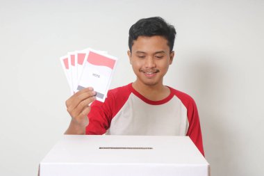 Heyecanlı Asyalı adamın portresi oy pusulasını sandığa yerleştirip koyuyor. Endonezya cumhurbaşkanı ve hükümeti için genel seçimler veya Pemilu. Beyaz arkaplanda izole edilmiş resim