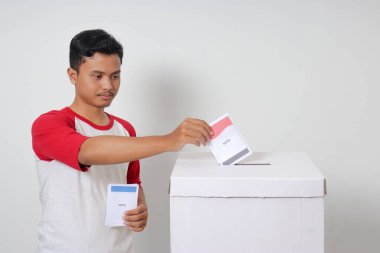 Heyecanlı Asyalı adamın portresi oy pusulasını sandığa yerleştirip koyuyor. Endonezya cumhurbaşkanı ve hükümeti için genel seçimler veya Pemilu. Beyaz arkaplanda izole edilmiş resim