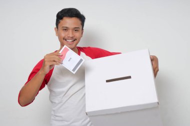 Heyecanlı Asyalı adamın portresi oy pusulasını sandığa yerleştirip koyuyor. Endonezya cumhurbaşkanı ve hükümeti için genel seçimler veya Pemilu. Beyaz arkaplanda izole edilmiş resim