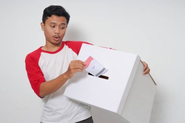 Heyecanlı Asyalı adamın portresi oy pusulasını sandığa yerleştirip koyuyor. Endonezya cumhurbaşkanı ve hükümeti için genel seçimler veya Pemilu. Beyaz arkaplanda izole edilmiş resim