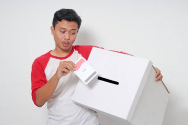 Heyecanlı Asyalı adamın portresi oy pusulasını sandığa yerleştirip koyuyor. Endonezya cumhurbaşkanı ve hükümeti için genel seçimler veya Pemilu. Beyaz arkaplanda izole edilmiş resim