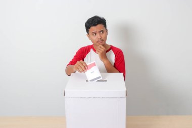 Heyecanlı Asyalı adamın portresi oy pusulasını sandığa yerleştirip koyuyor. Endonezya cumhurbaşkanı ve hükümeti için genel seçimler veya Pemilu. Beyaz arkaplanda izole edilmiş resim