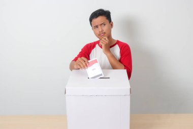 Heyecanlı Asyalı adamın portresi oy pusulasını sandığa yerleştirip koyuyor. Endonezya cumhurbaşkanı ve hükümeti için genel seçimler veya Pemilu. Beyaz arkaplanda izole edilmiş resim
