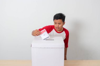 Heyecanlı Asyalı adamın portresi oy pusulasını sandığa yerleştirip koyuyor. Endonezya cumhurbaşkanı ve hükümeti için genel seçimler veya Pemilu. Beyaz arkaplanda izole edilmiş resim
