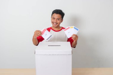 Heyecanlı Asyalı adamın portresi oy pusulasını sandığa yerleştirip koyuyor. Endonezya cumhurbaşkanı ve hükümeti için genel seçimler veya Pemilu. Beyaz arkaplanda izole edilmiş resim
