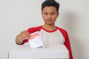 Heyecanlı Asyalı adamın portresi oy pusulasını sandığa yerleştirip koyuyor. Endonezya cumhurbaşkanı ve hükümeti için genel seçimler veya Pemilu. Beyaz arkaplanda izole edilmiş resim