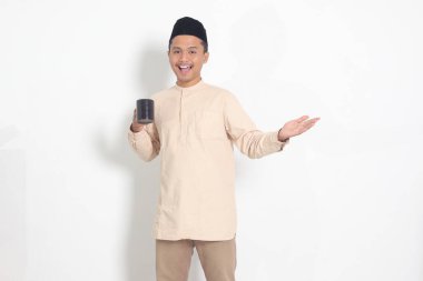 Koko tişörtlü çekici Asyalı Müslüman adamın portresi. Kaslı, fincanı tutan, içme suyu içen, oruç tuttuktan sonra susuzluğunu gideren. Beyaz arkaplanda izole edilmiş resim